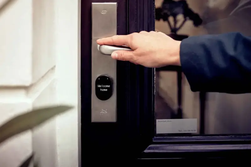 Mão de pessoa acionando fechadura digital inteligente em porta